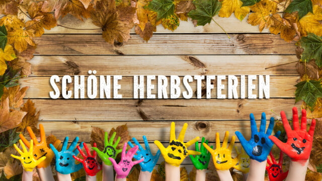 in bunten Farben angemalte Kinderhände herbstlich dekoriertem Holzschild und der Aufschrift "Schöne Herbstferien"